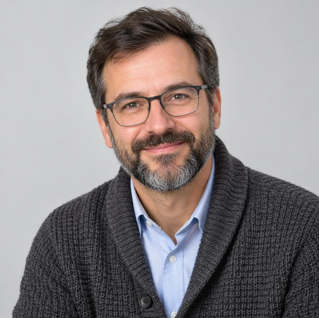 Studio portrait of a Slovenian male psychologist wearing glasses and a cardigan